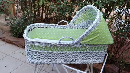 Lovely white cane bassinet on a stand.