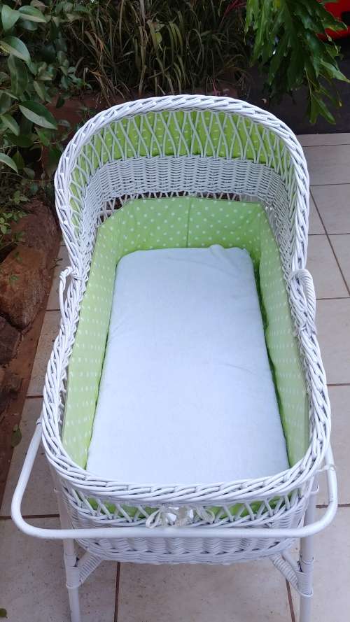 Lovely white cane bassinet on a stand.
