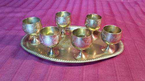 Set of small brass tot goblets on a tray.