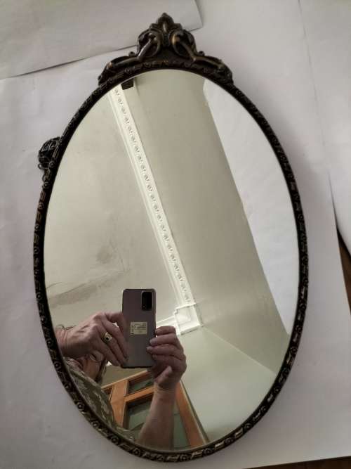 Vintage Gold Oval Mirror With Ornate Detail on top of The Mirror.