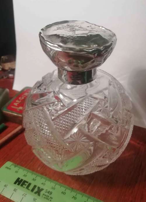 CUT GLASS BOTTLE WITH SILVER TOP.