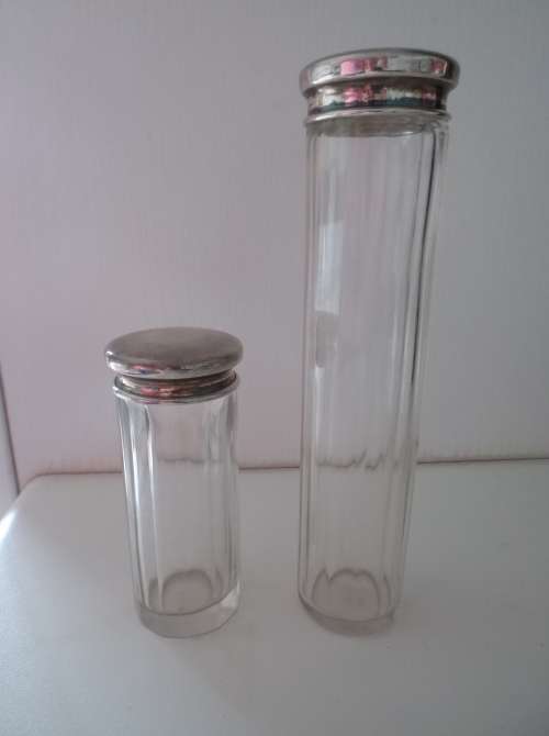 Two long glass containers with solid silver tops.
