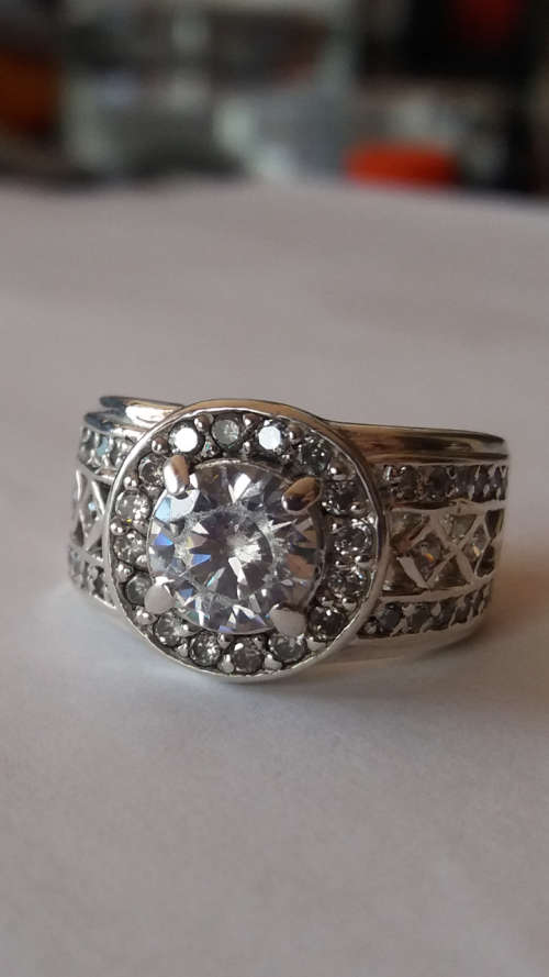 A BEAUTIFUL STERLING SILVER RING SET WITH A CENTER GEM AND GORGEOUS GEMS AROUND.