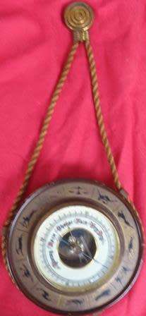A barometer with signs of the zodiac as a surround and a fancy hanging rope