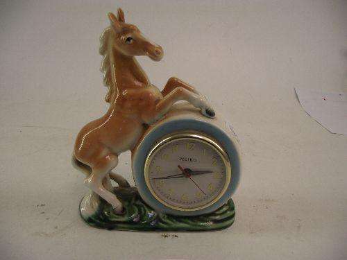 A RARE POTTERY MANTLE CLOCK MODELLED AS A PRANCING HORSE, 17CMS TALL, FITTED WITH A KEYWOUND MEIKO C