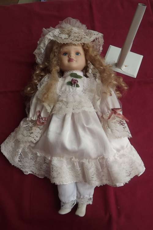 Porcelain doll with blond hair - soft body.One foot cracked. 42cm long with stand