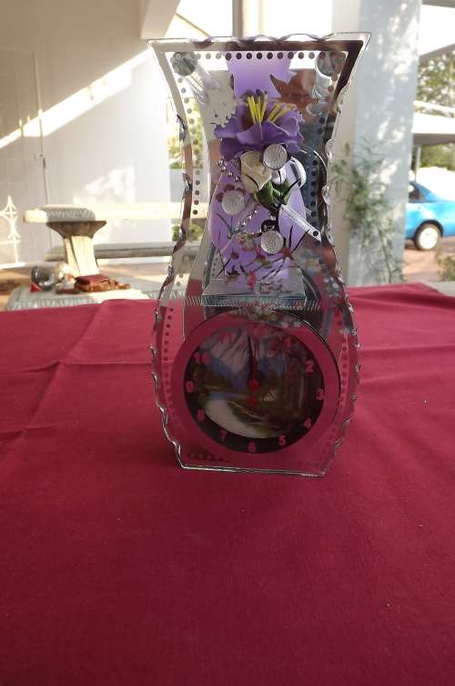 Ornament with purple flower vase on clock.Mirror  at back.Perspex on front.20cm high.New condition