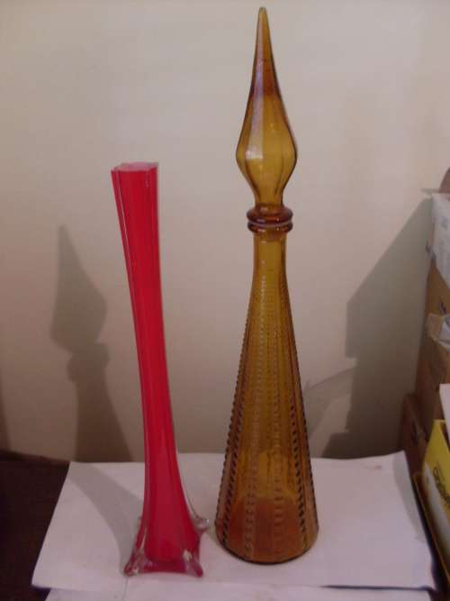 A TALL DECORATIVE DECANTER WITH STOPPER AND A LONG STEM RUBY RED VASE
