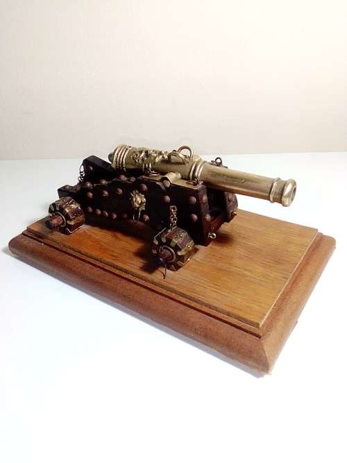 A Brass Canon with crest on Barrel, mounted on a wooden plinth with 4 feet.