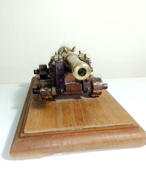 A Brass Canon with crest on Barrel, mounted on a wooden plinth with 4 feet.