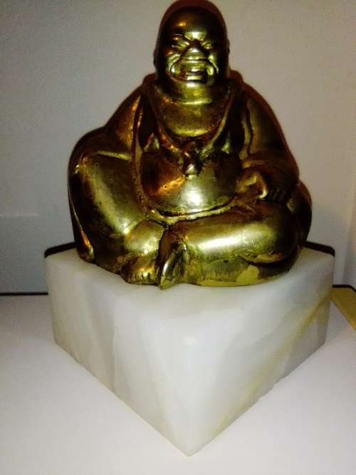 A laughing solid Brass Buddha on white Marble plinth. Symbol of prosperity in Feng Shui.