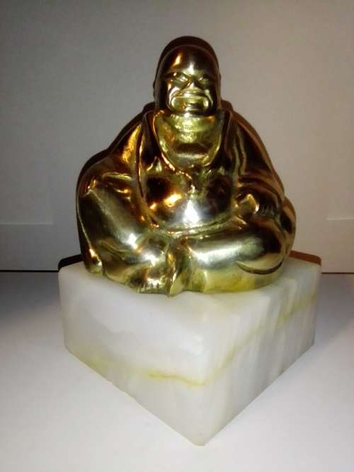 A laughing solid Brass Buddha on white Marble plinth. Symbol of prosperity in Feng Shui.