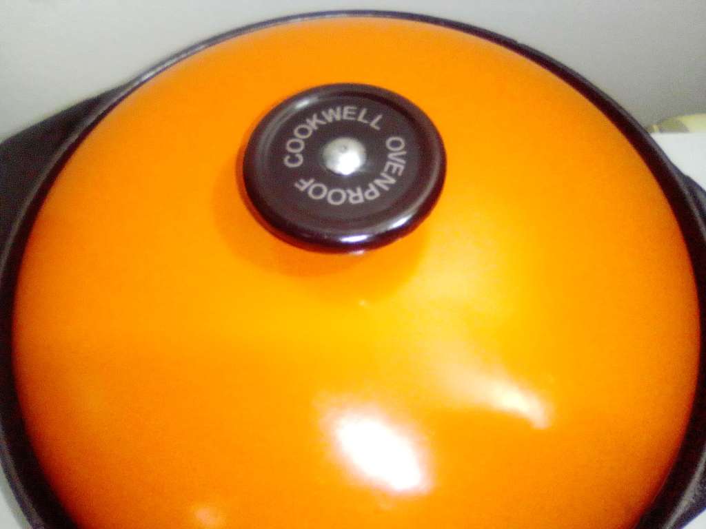 A well-used and in pristine orde, vintage Cookwell orange enameled lidded cast iron cooking pot No8.